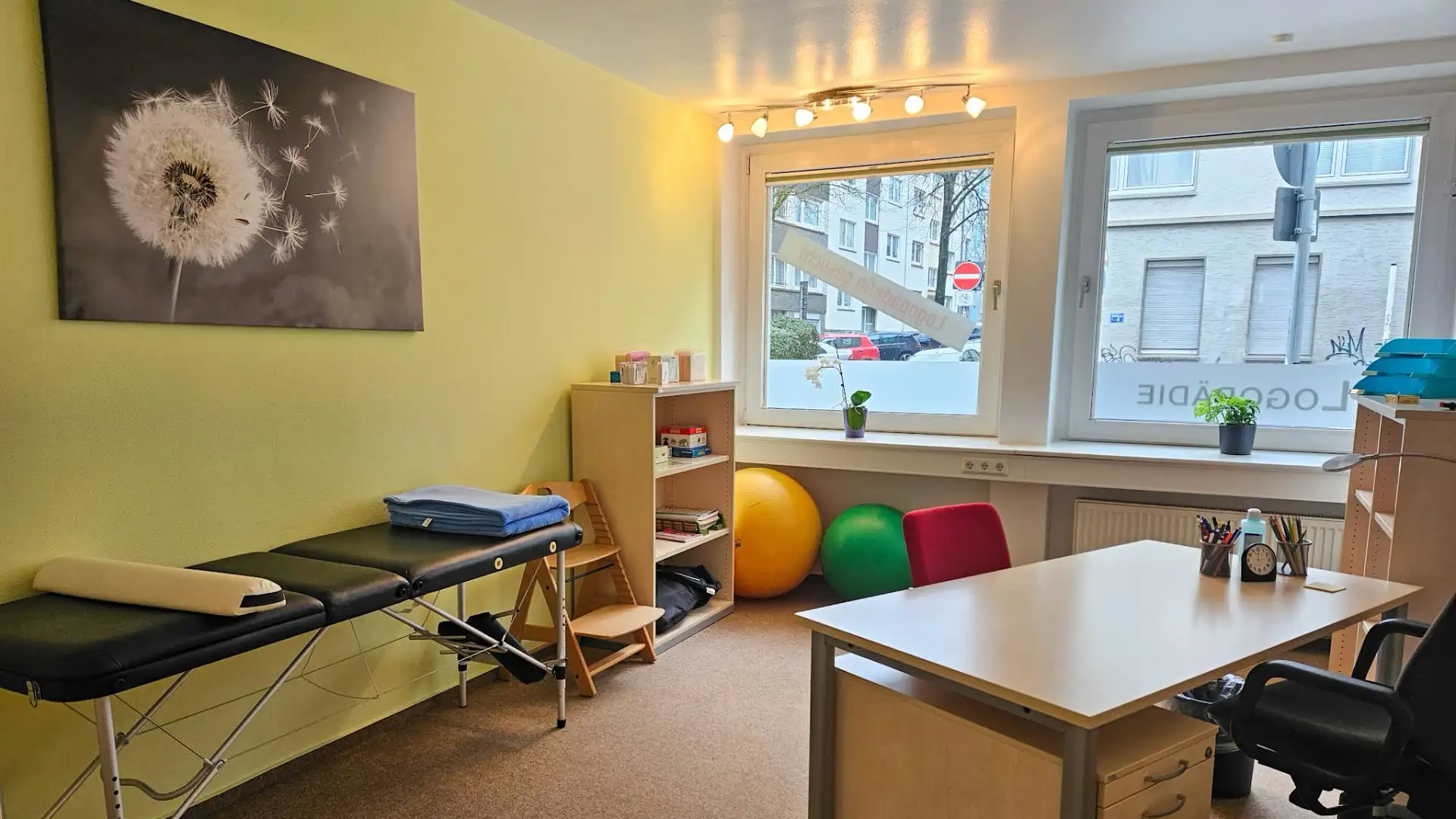Therapieraum der Praxis für Sprachtherapie Clemens in Essen mit Therapieliege, Schreibtisch und Therapiebällen