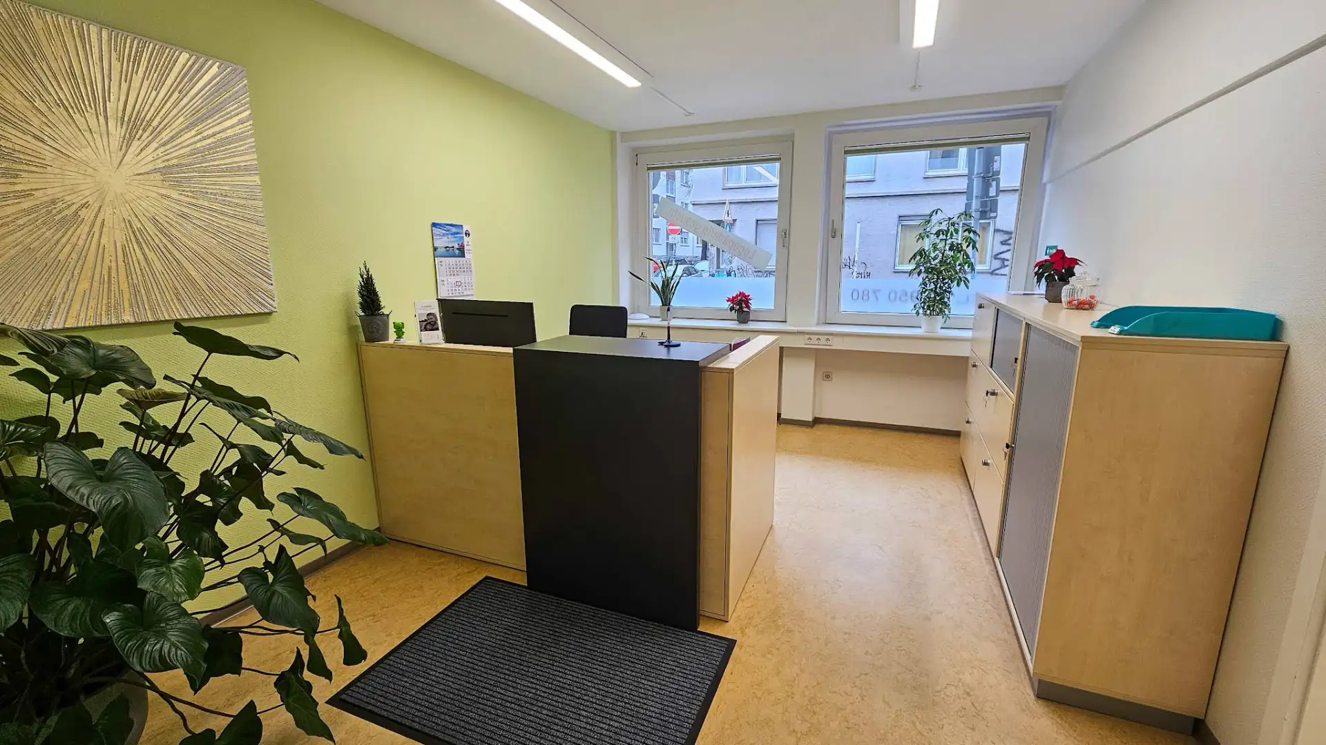 Heller Empfangsbereich der Praxis für Sprachtherapie Clemens in Essen mit Rezeptionstresen, großen Zimmerpflanzen und freundlicher Atmosphäre